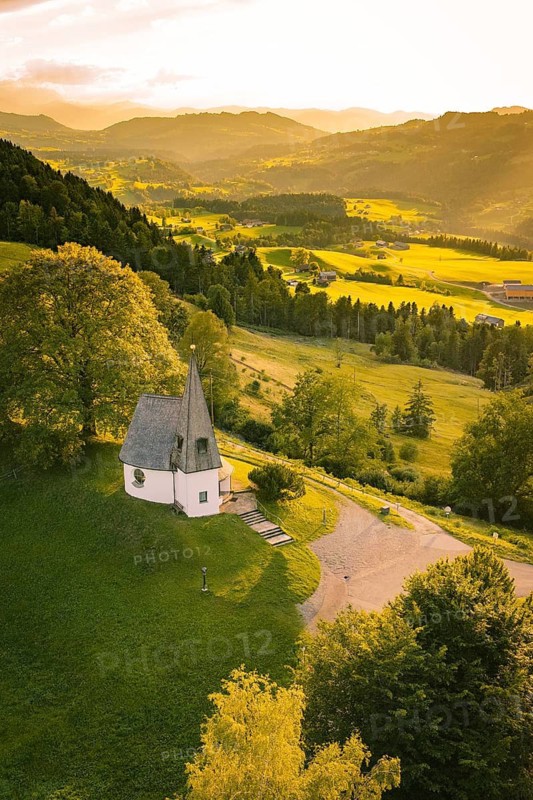 Chapel on green hill with view over forests and fields in the evening light, Bruder Klaus Kapelle, Allgäu, Bavaria, Germany