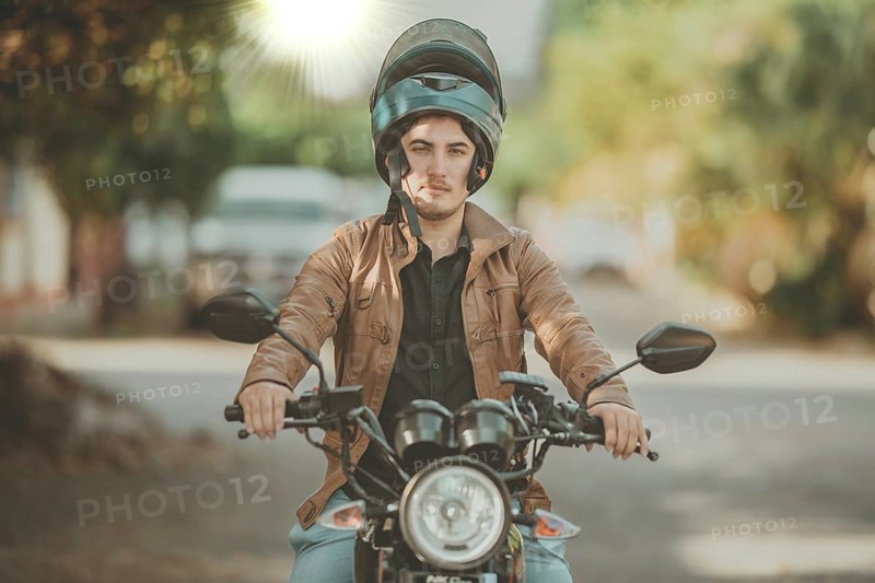 Portrait of smiling male motorcyclist on his motorcycle on the road. Portrait of a Latin motorcyclist on his motorcycle on the asphalt