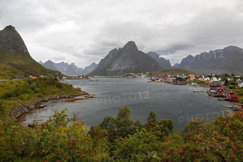 Picturesque Reinefjorden bay with Reinebringen mountain on the left and the fishing village of Reine under a cloudy sky, Reine, Lofoten, Norway