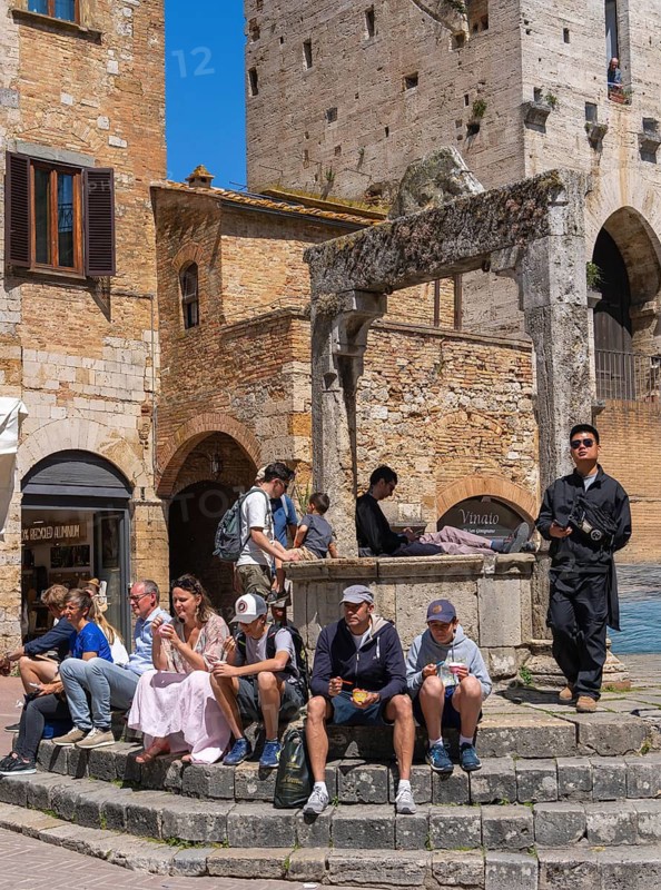 Tourists around the market square with old fountain and other sights in San Gimignano, Tuscany, Italy