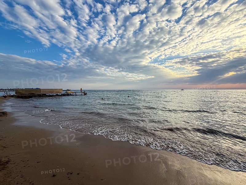 Beach landscape with waves and a jetty under a cloudy sky at sunset, Side, Manavgat, Antalya Province, Turkey