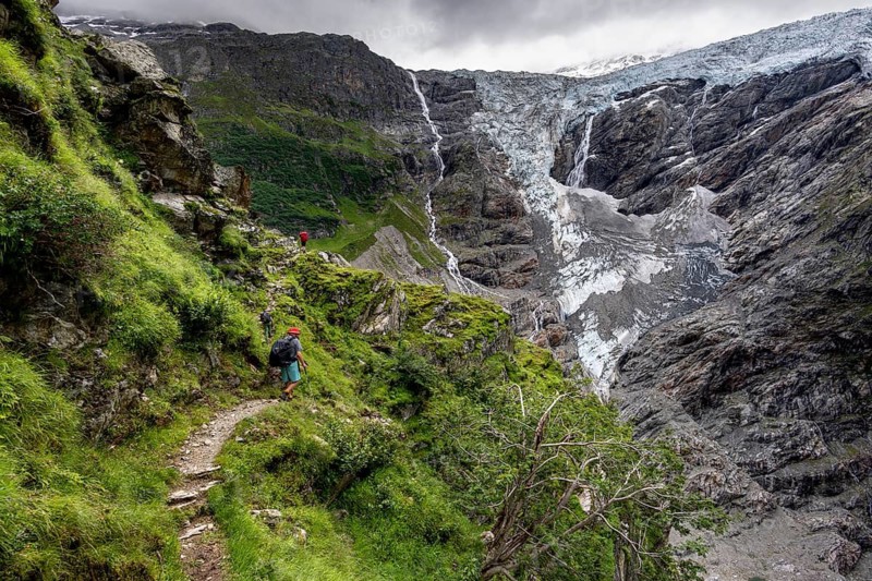 Mountaineers on a hiking trail, cloudy mountain landscape with Grindelwald-Fiescherfirn glacier, Bernese Alps, Bernese Oberland, Switzerland