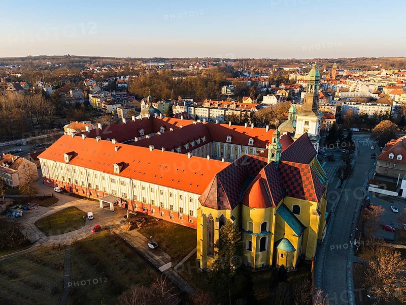 Drone aerial view of the Sanctuary of Saint Hedwig in Trzebnica, Poland, featuring the historic baroque basilica and monastic complex at sunset