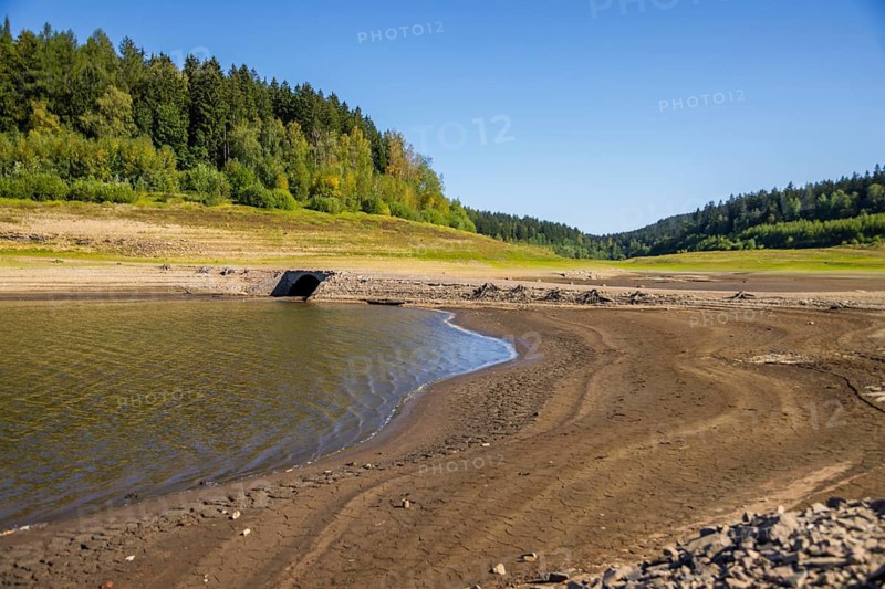 A historic arched bridge appears through low water in the Lehnmühle dam, Dippoldiswalde, Saxony, Germany