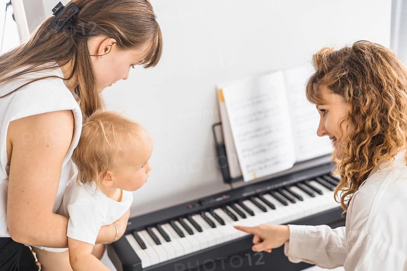 A mother and child interact at a piano, focusing on a shared learning moment