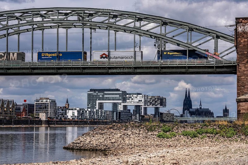 Low water in the Rhine near Cologne, view from the right bank of the Rhine across the Boller Wiesen, heading north, south bridge, railway bridge, freight train, skyline of the city center with the cathedral, inland navigation is severely restricted, only a few ships sail, then with a significantly reduced load, on the day of recording it was the lowest Rhine level ever measured in Cologne, 60 cm, North Rhine-Westphalia, Germany