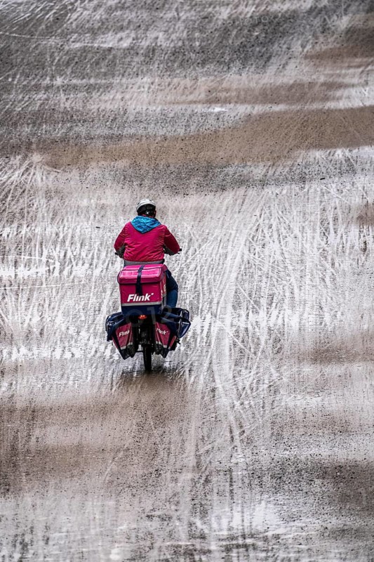 Dirt road, with many traces of two-wheelers, footprints, delivery service Flink Radkurier, wet, after rain, parallel, mixed up