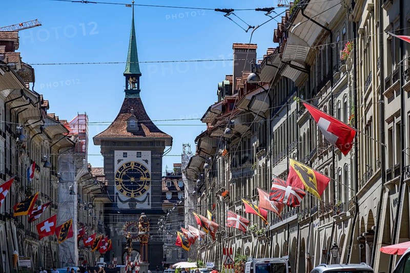 Kramgasse with historic houses decorated with cantonal flags and Swiss national flags, back clock tower Zytglogge, old town, Bern, Canton of Bern, Switzerland