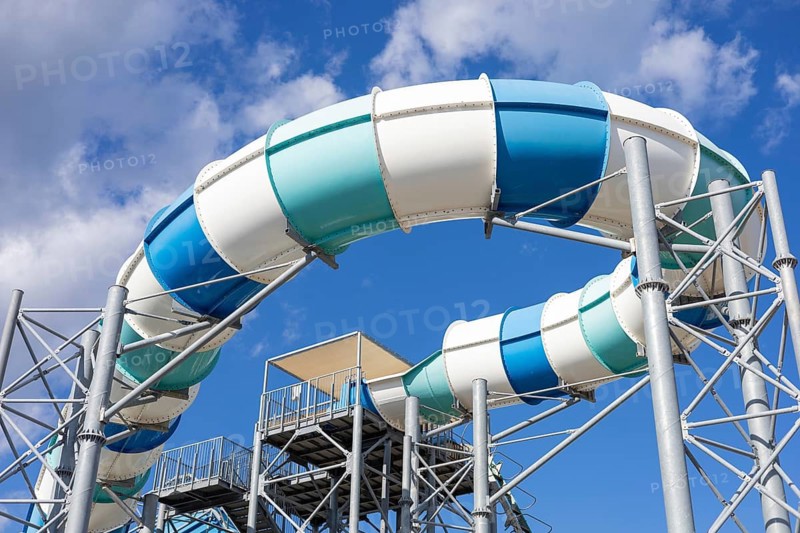 Bright sunlight shines over a fun water slide in a hotel water park in Turkiye. Families and friends gather to enjoy the exciting water attractions during a warm summer day. Active rest in aqua park