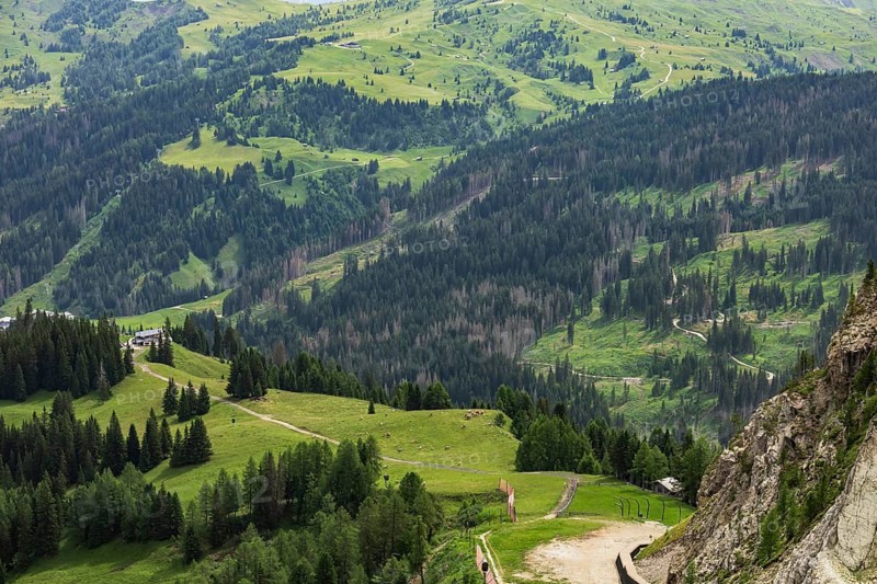 Aerial view of a valley with a village surrounded by green fields and forests. Dolomites, Italy.