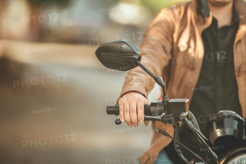 Hands of male motorcyclist on the handlebars on the road. Hands of moto biker on the handlebars of a motorcycle in the street