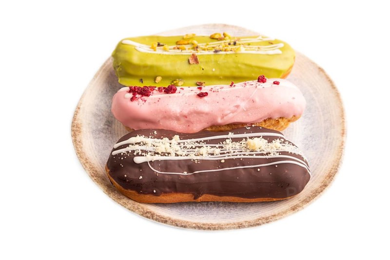 Glazed Eclairs on brown concrete isolated on white, side view, close up
