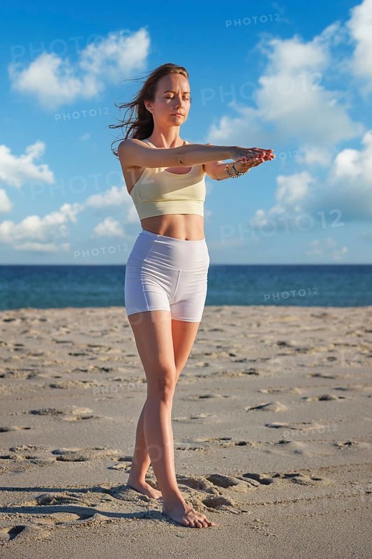 Beach scene featuring a woman, yoga, tadasana, mountain pose, practicing yoga, and arm extension