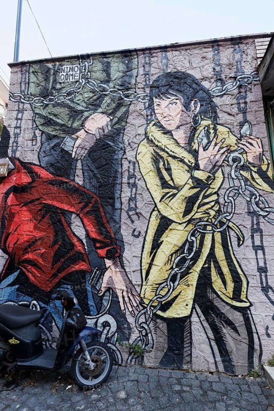 Young woman frees herself from chains wall painting street art artist Nino Come, Rione Sanità, Naples, Campania region, Italy