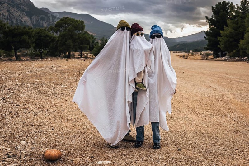 Family dressed as playful ghosts outdoors celebrating Halloween. Creative homemade costumes, seasonal traditions, spooky fun and cozy autumn lifestyle concept with modern holiday aesthetics.