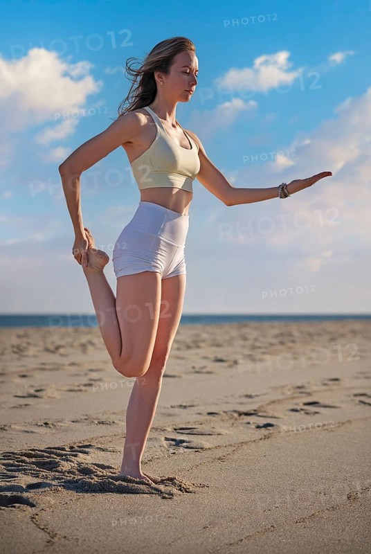 Sandy beach scene featuring a young woman, natarajasana, female yogi, dancer pose, a woman, and yoga