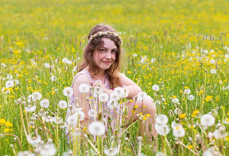 Portrait of a smiling girl sitting in a flower meadow, Mondsee, Salzkammergut, Austria