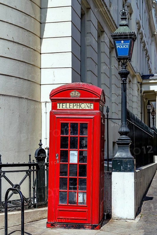 A red K2 telephone kiosk designed by Giles Gilbert Scott in 1927 stands beside a Metropolitan Police lamp post at Charing Cross Police Station. The surviving 1910 lamp column commemorates the start of George V's reign and is Grade II listed. London, England, United Kingdom