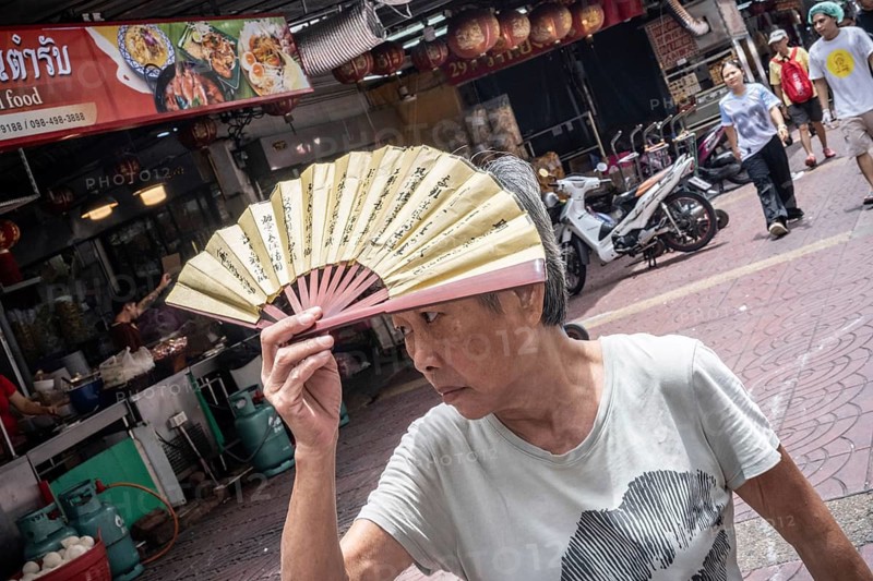 Bangkok, Thailand. August 24th 2026. An elderly lady shields her face from the sun during August heat in Chinatown, Bangkok, Thailand, Asia