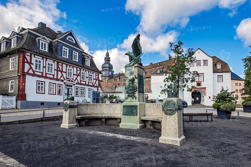 Original historic war memorial converted into a peace memorial in 2023 Memorial to wars of unification with eagle and relief of Emperor Wilhelm I and memorial plaque with inscription To the unforgettable hero emperor Wilhelm I and the sons who fell for the fatherland the grateful county of Wittgenstein-Berleburg, Bad Berleburg, old half-timbered house on the left, gatehouse of Castle Residenzschloss Berleburg from the 16th century to the city side, Bad Berleburg, North Rhine-Westphalia, Germany