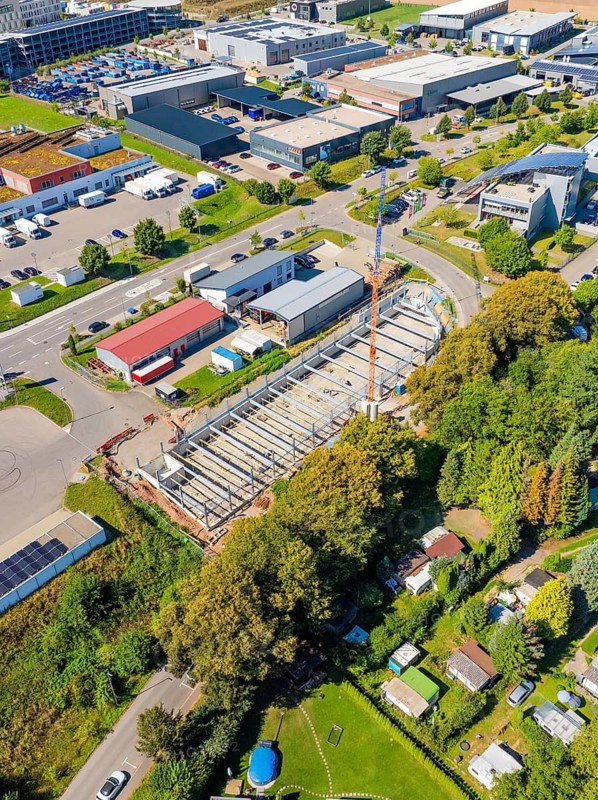 Aerial view showing a construction site in an urban area with industrial buildings and vegetation, Parkhaus Bau, Calw, Germany