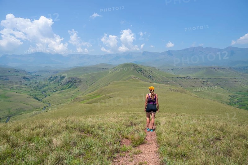 Green hills and valleys, young woman hiking through landscape, Worlds View Hike, Drakensberg, South Africa