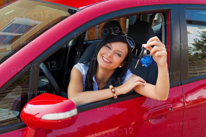 Young woman with new car and car key