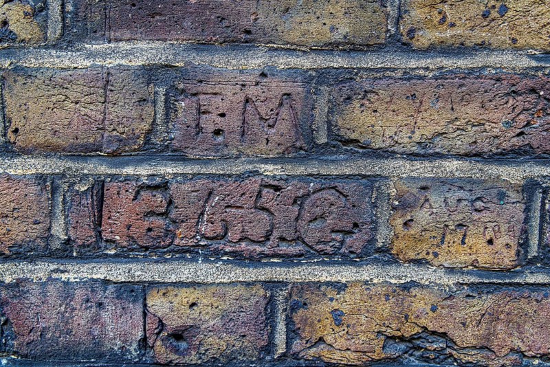 Secret London. Carved initials sit above a scratched collar number on adjoining bricks along Myddelton Passage in Clerkenwell, part of the wall's collection of nineteenth century markings left by patrolling Metropolitan Police officers of G Division. London, England, United Kingdom