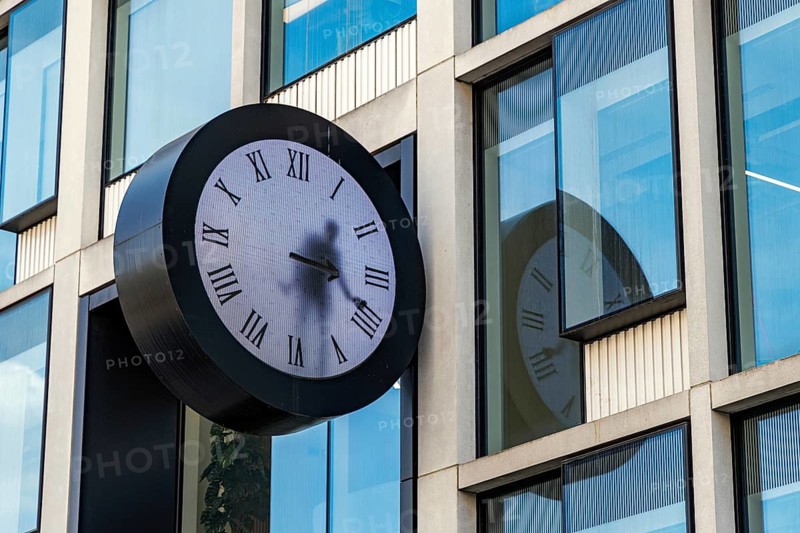 This clock at 50 Eastbourne Terrace is Real Time by Dutch artist Maarten Baas, a video artwork in which a costumed figure appears to repaint the hands by hand each minute, its Victorian dress alluding to Paddington architect Isambard Kingdom Brunel, London, England, United Kingdom