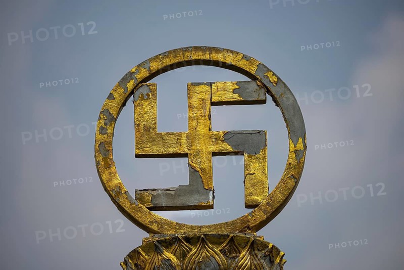 Golden swastika symbol in traditional Buddhist form, symbol of luck, protection and the cosmic order of Buddha's teaching, the circular bezel and lotus ornaments emphasize purity and spiritual perfection. Chee Chin Khor Temple, Bangkok, Thailand