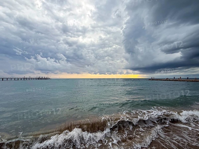 Dramatically cloudy sky over turbulent sea, waves gently hitting the shore, Side, Manavgat, Antalya Province, Turkey