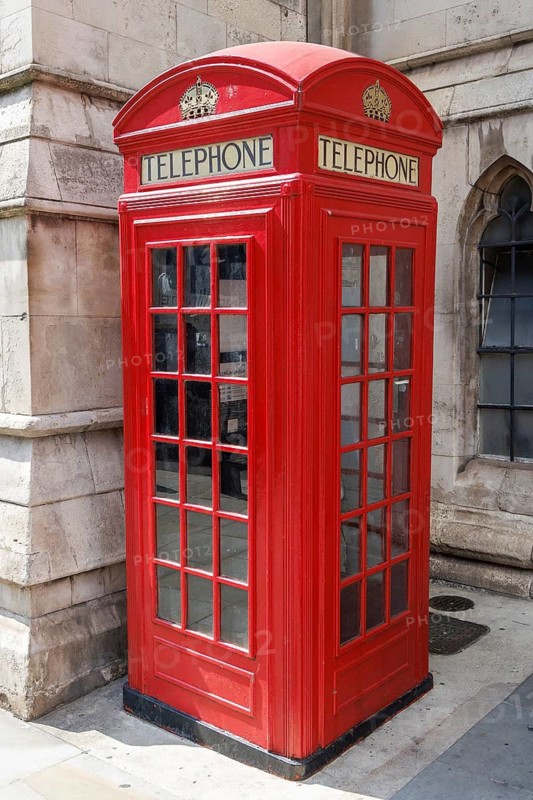 A cast iron K2 telephone kiosk, designed by Sir Giles Gilbert Scott and introduced from 1926, stands against a stone facade near the Royal Courts of Justice, its domed roof, glazed panels and crown motifs a familiar feature of London's twentieth century street scene. London, England, United Kingdom