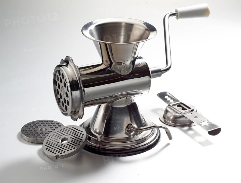 Meat grinder with pastry attachment and various accessories, against white background, studio shot