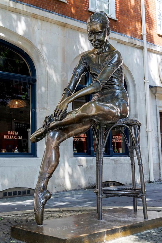 Enzo Plazzotta's bronze Young Dancer, unveiled in 1988, depicts Royal Ballet dancer Katie Pianoff seated on a stool tying her ballet shoe. The Italian-born sculptor's estate gifted the statue to Broad Court opposite the Royal Opera House. London, England, United Kingdom