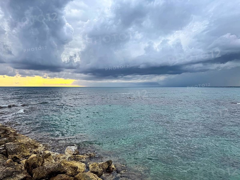 Dark clouds announce a storm over the turquoise sea at sunset, Side, Manavgat, Antalya Province, Turkey