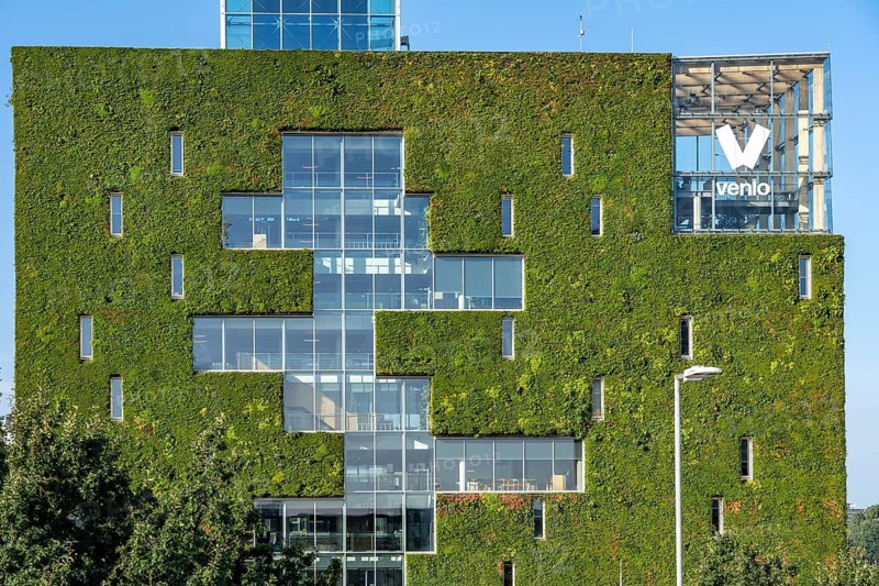 Green north façade of Stadskontoor Venlo, city administration building, from 2016, approx. 2200 square meters of the façade are green, various types of plants hang in plant modules in front of the actual façade, a combined climate concept, a circulatory system, with a greenhouse on the upper floors, thermal energy from the underground parking garage, a so-called solar chimney, is the building air cooled in summer and heated in winter, rainwater is used to irrigate the green building façade, the entire project was built according to the Cradle-to CRADLE concept built, Venlo, Limburg, Netherlands