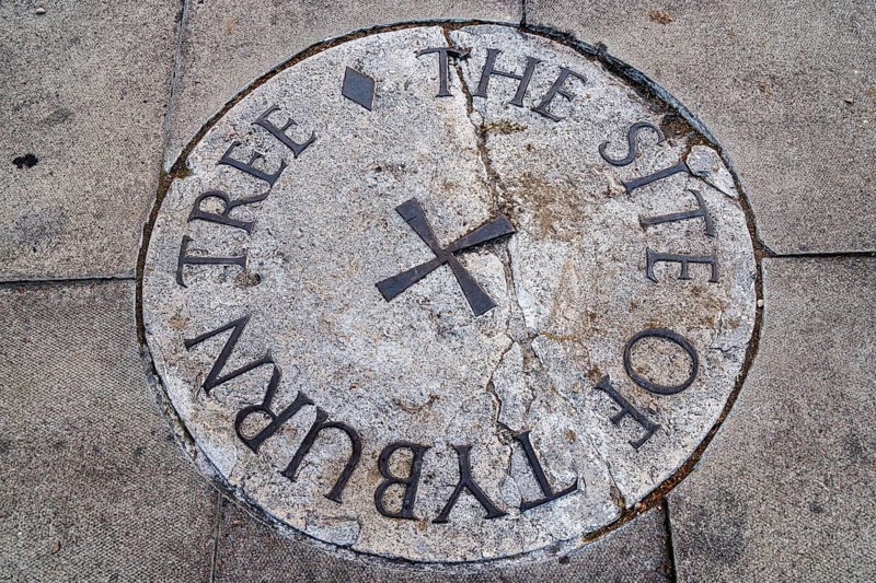 Secret London, Weathered stone plaque set into the pavement marking the historic Tyburn Tree execution site near Marble Arch, London, United Kingdom