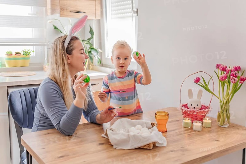 Mother and little daughter painting Easter eggs at home. family tradition, spring celebration and holiday preparation