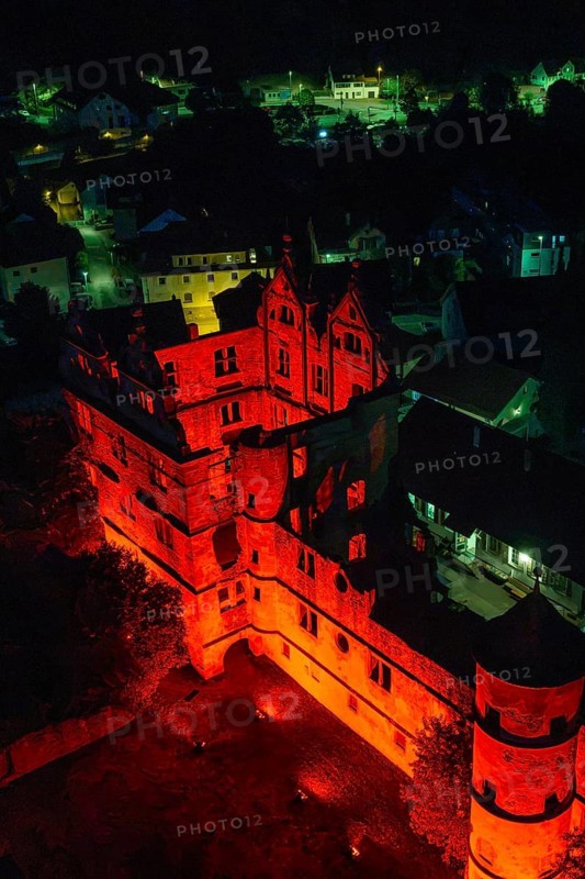 Historic building bathed in red light at night, atmospherically illuminated in the midst of an urban landscape, Calwer Klostersommer Festival, Hirsau Abbey, Calw, Germany