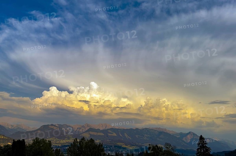 Yellowish cloud front with cumulus cluster wokes pile up over the edge of the Alps with high concentration of hailstones and ice crystals in thunderclouds refract sunlight produce intense yellow color in the sky, Bavaria, Germany