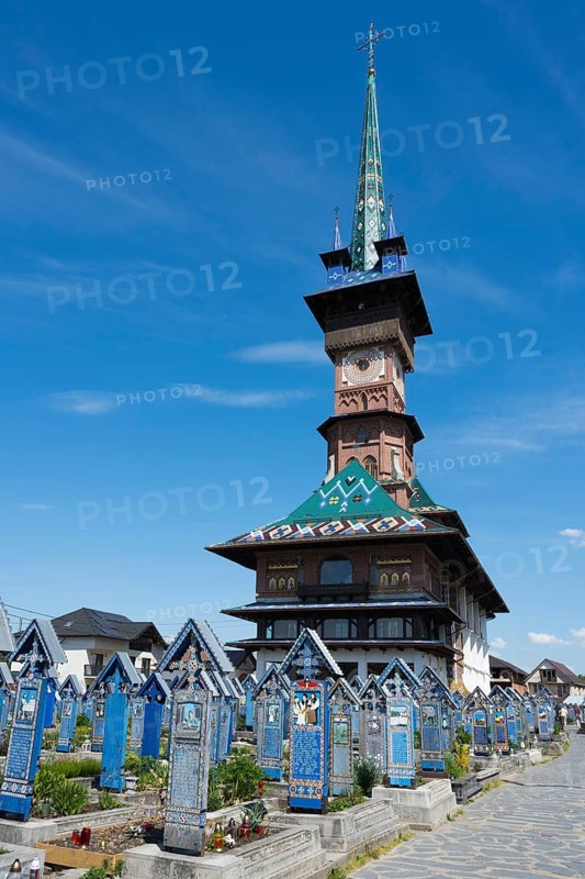 Tall church with colorful tower surrounded by colorful tombs under a clear sky, traditional wooden graves, Happy Cemetery, Cimitirul Vesel, Sapân?a, Sapanta, Maramures, Maramures, Maramures, Romania