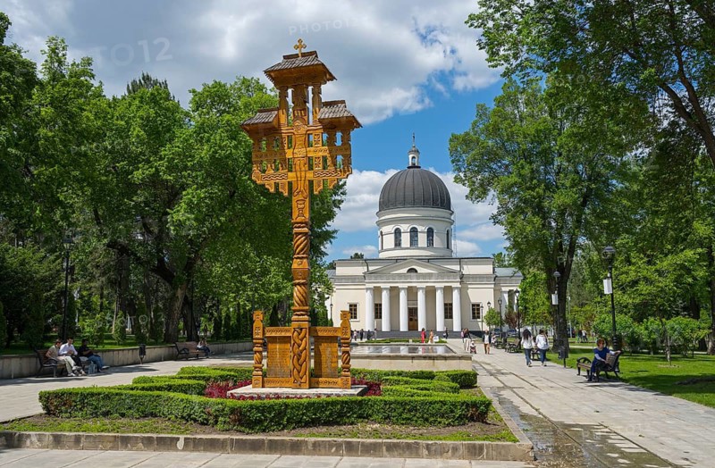 Cathedral in the park with wooden sculpture in the foreground under blue sky and green treesCathedral of the Nativity of the Lord, Catedrala Na?terea Domnului, neoclassical Moldovan Orthodox church, traditional wooden corridor cross or consolation cross, Chisinau, Chisinau, Chisinau, Republic of Moldova, Moldova, Eastern Europe