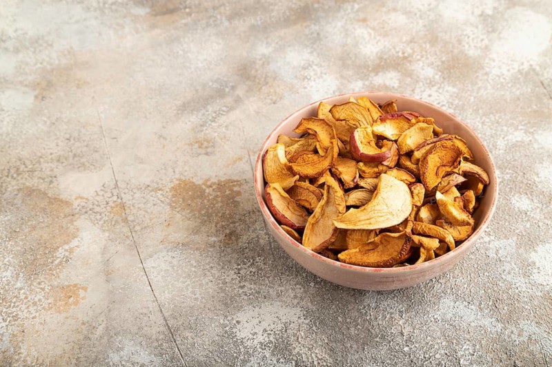 Dried Apples in ceramic bowl on brown concrete background. Side view, copy space, flat lay. healthy food, minimalism. sweet