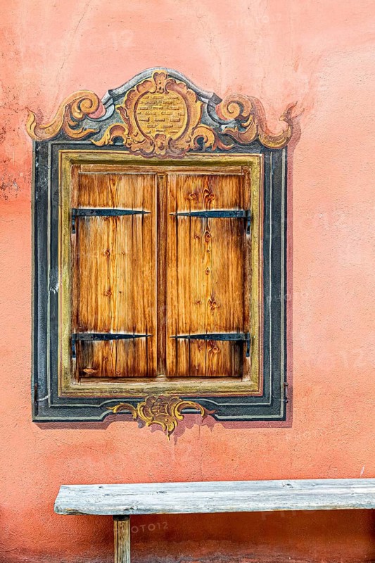 Wooden window with baroque wall painting on an orange wall with rustic character