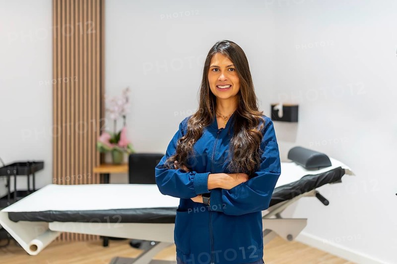 Smiling female professional standing confidently with arms crossed in a modern aesthetic clinic or medical spa, ready for beauty and skin care treatments
