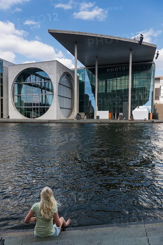 Woman sitting on the banks of the Spree at Marie-Elisabeth-Lüders-Haus in the government district, Berlin