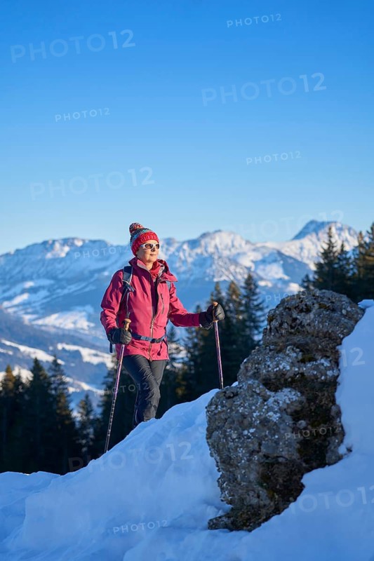 Nice and active senior woman snowshoeing in in the snow covered Allgaue alps above the valley of river Iller, Immenstadt, Bavaria, Germany