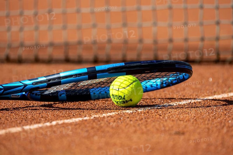 Tennis icon: close-up of a tennis ball and tennis racket on a clay court