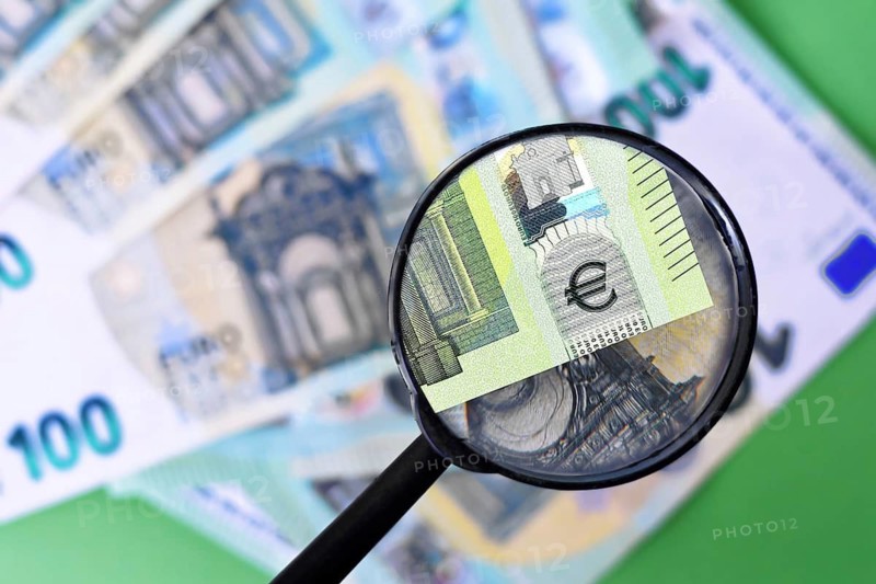 Magnifying glass checking authenticity of euro banknote