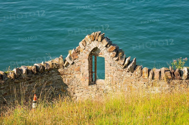 Stone ruin by the sea with a window in a green landscape, Howth, Ireland